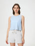 Model wearing a blue cropped active tank top with white shorts, showcasing a stylish and comfortable workout look.
