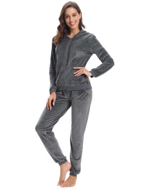 Woman modeling a cozy knit two-piece set, featuring a hooded long sleeve top and matching pants in soft gray.