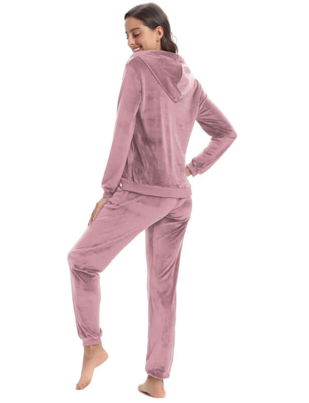 Woman wearing a cozy knit two-piece set in soft pink, featuring a hooded jacket and relaxed-fit pants, perfect for leisure.