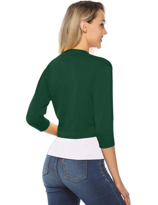 Woman wearing a green 3/4 sleeve cropped cardigan from the back, paired with jeans.