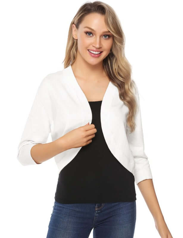 Woman wearing a white 3/4 sleeve cropped cardigan over a black top, showcasing a stylish layering option.