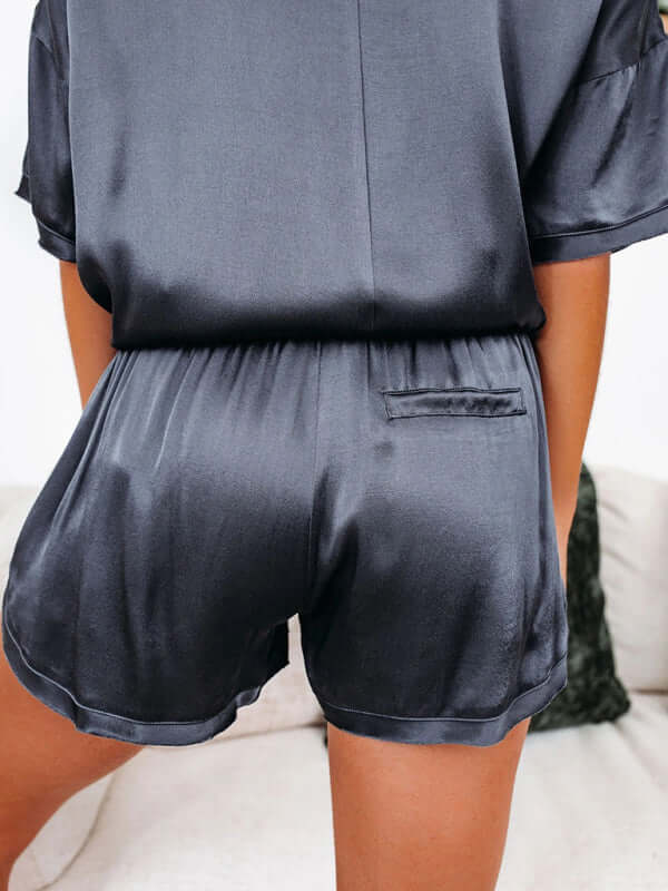 Women's satin pajama set featuring short-sleeved top and shorts, showcasing sleek back design and welt pocket.