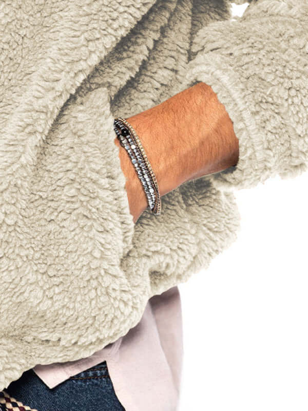 Close-up of a man's wrist wearing a stylish black beaded bracelet, showcased against a cozy light-colored fuzzy jacket.