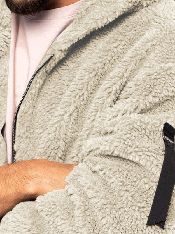 Close-up of a man wearing a casual warm hooded jacket in soft grey material, showcasing fabric texture and zipper.