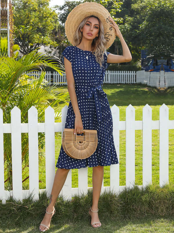 Model wearing a women's woven polka dot pleated midi dress in navy, perfect for spring-summer style.