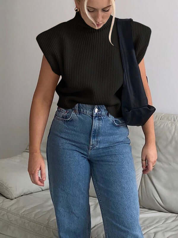 Woman wearing a black solid color turtleneck short-sleeve sweater top with blue jeans, showcasing a casual style.