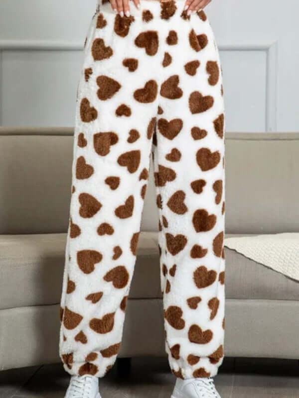 Cozy coral fleece pajama pants featuring a playful brown heart pattern, perfect for autumn-winter lounging.