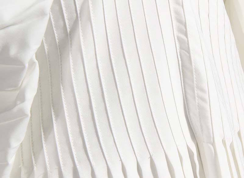 Close-up of the pleated fabric of a white Sakiya long sleeve shirt dress, showcasing soft cotton texture and elegant design.