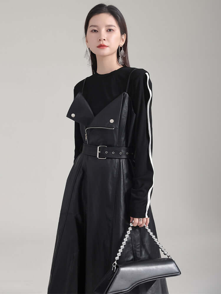 Model wearing a knee-length Musset Vegan Leather Dress in black with a spaghetti strap and fierce A-line silhouette.