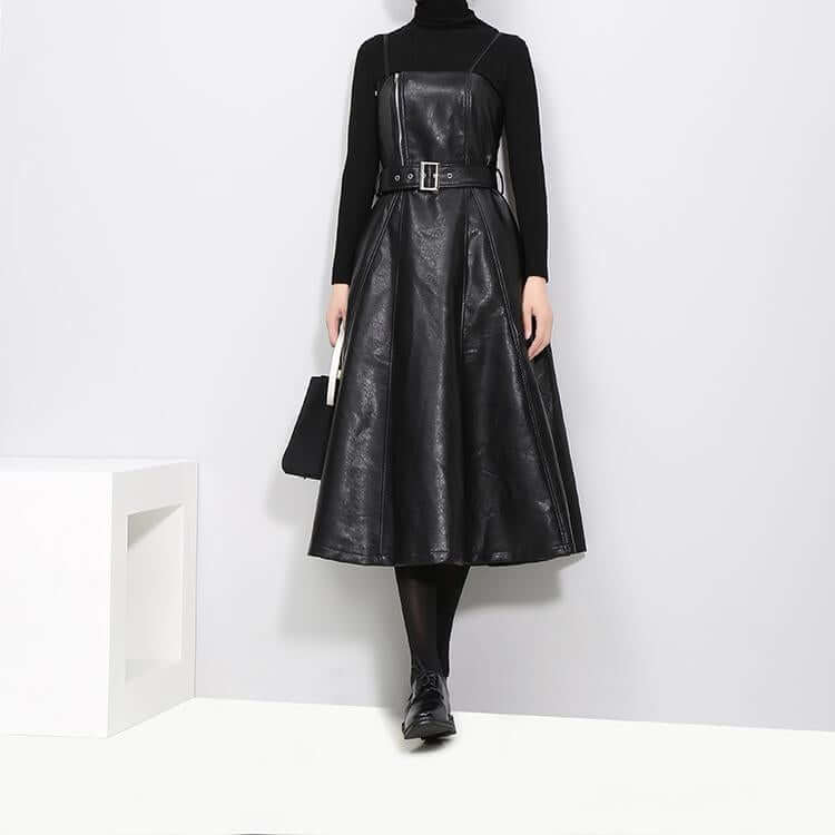 Stylish women in a knee-length black vegan leather dress with a fitted bodice and A-line skirt, styled with a turtleneck.