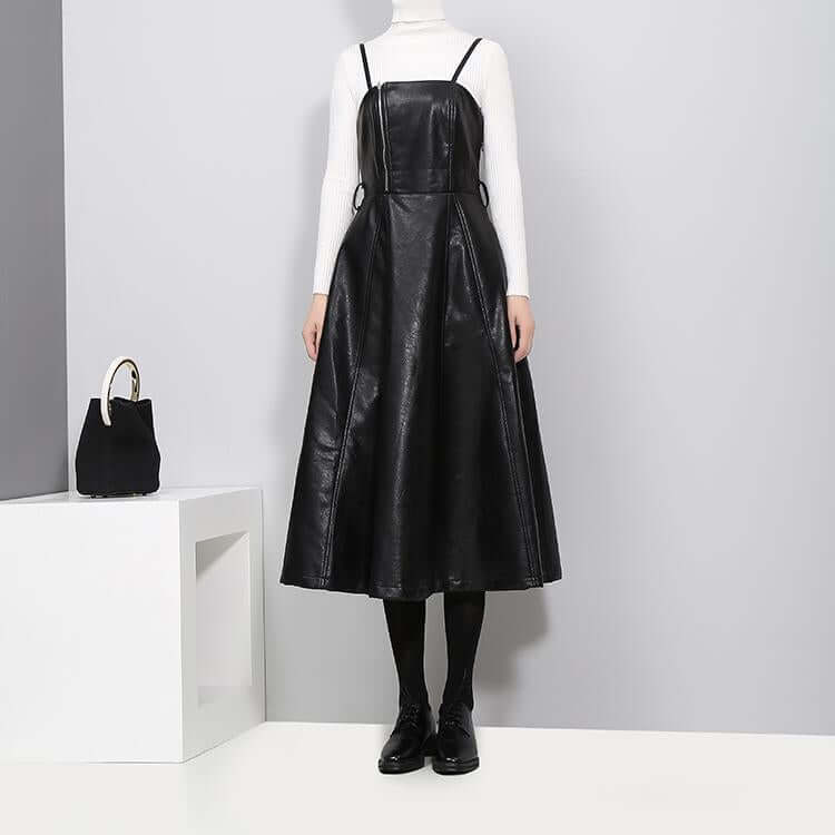 Knee-length black vegan leather dress with spaghetti straps and A-line silhouette, styled with a white turtleneck.