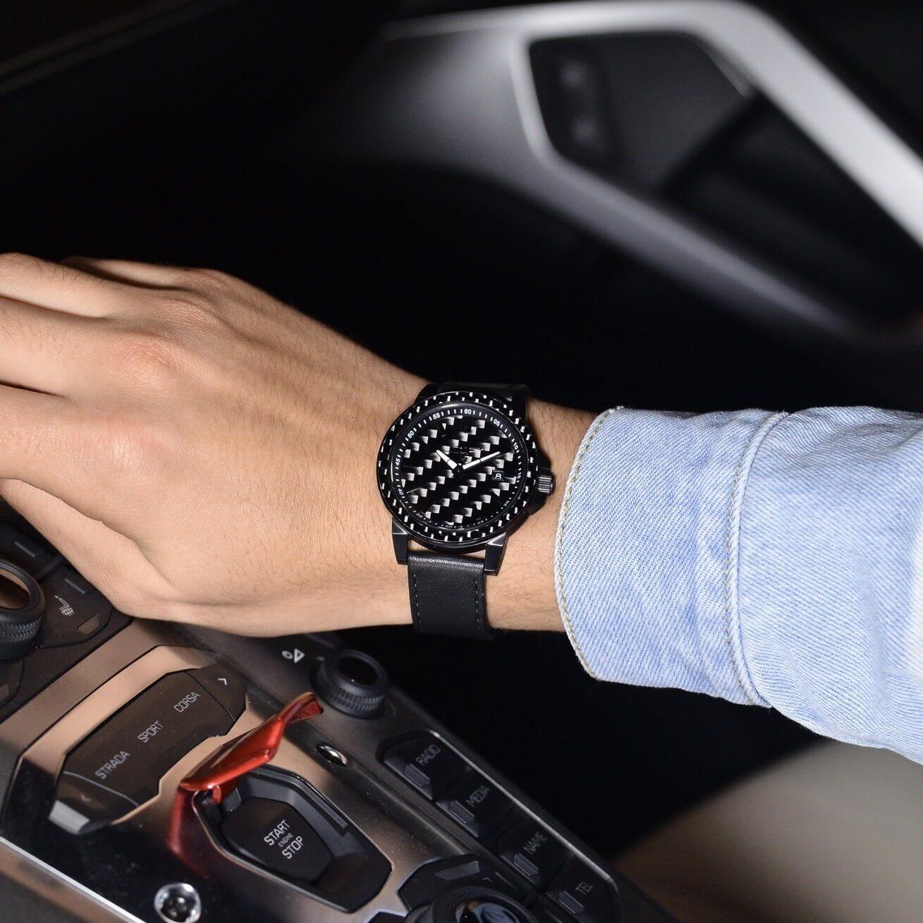 Close-up of STEALTH APOLLO carbon fiber watch on a man's wrist in a luxury car interior.