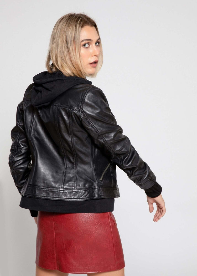 Back view of Annalise Womens Leather Jacket featuring fleece hoodie, black lambskin leather, and a stylish red skirt.